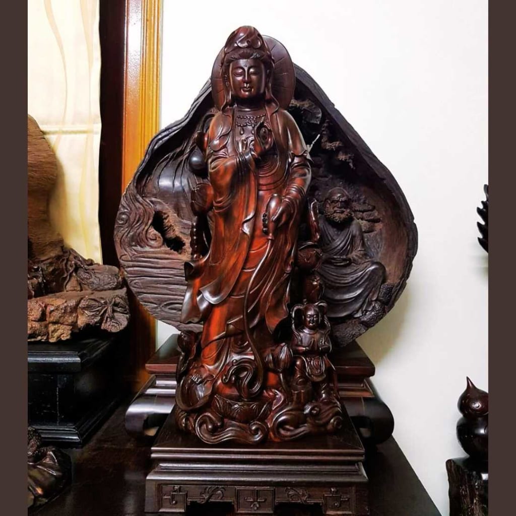 Tượng Phật gỗ được đặt ở trên mặt bàn. Tay phải ngài bắt ấn, tay trái để trước bụng, tóc ngài xoăn và được búi cao