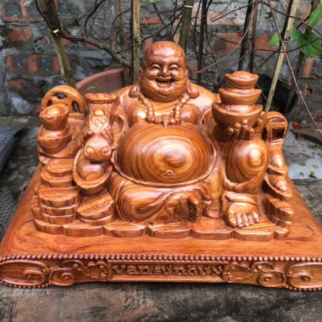 Bức tượng Phật Di Lặc bằng gỗ, ngồi trên một cái đế có ghi chữ "Vạn Sự Như Ý" và tay trái cầm ba thỏi vàng, tay phải cầm một cây gậy như ý